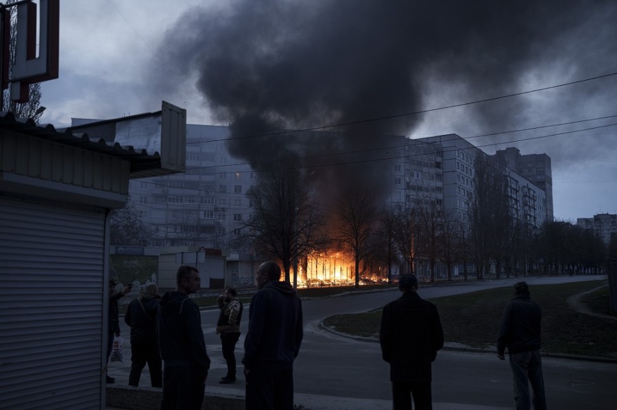 Varios residentes se paran afuera de sus apartamentos mientras las tiendas se queman después de un ataque ruso en Kharkiv, Ucrania. Foto AP/Felipe Dana