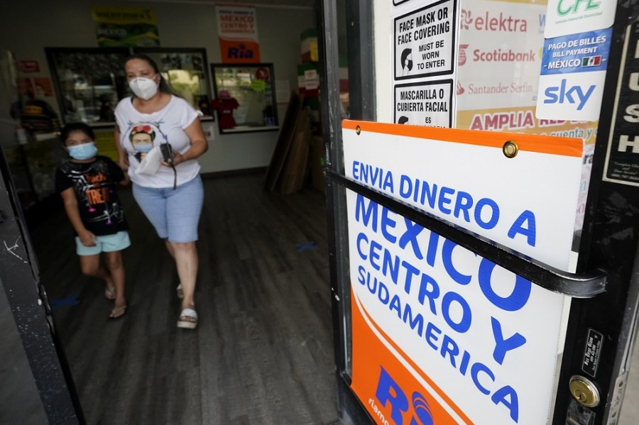 Una mujer sale de una tienda que ofrece el servicio de envío de remesas hacia Centro y Sudamérica en San Diego, California, durante la crisis sanitaria por la covid-19. Foto AP/Gregory Bull