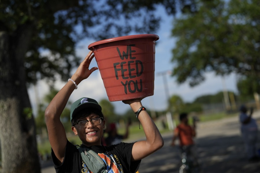 Un recolector de tomates, inmigrante originario de México, lleva un cubo de cosecha con la frase 