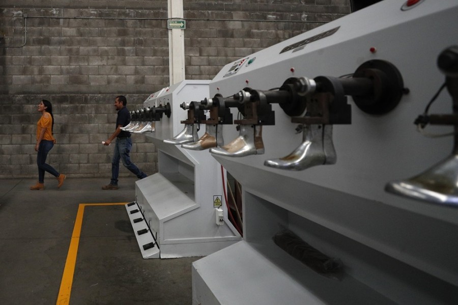 Un par de personas caminan dentro de la fábrica de zapatos Tennis Court en León, estado de Guanajuato, México. Foto AP/Rebecca Blackwell